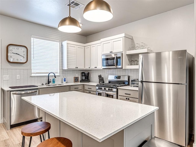 kitchen featuring sink, light stone counters, decorative light fixtures, appliances with stainless steel finishes, and backsplash