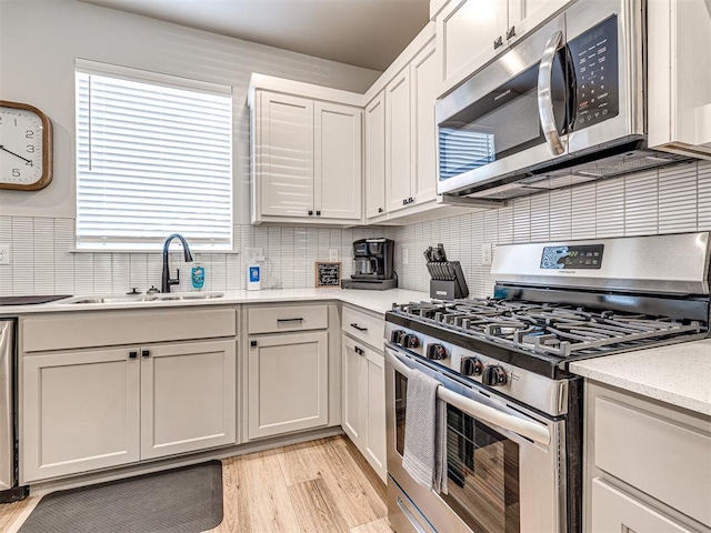 kitchen featuring decorative backsplash, light wood-type flooring, white cabinets, and appliances with stainless steel finishes