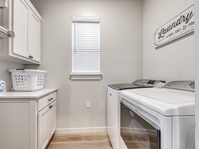 washroom with cabinets, washer and dryer, and light wood-type flooring