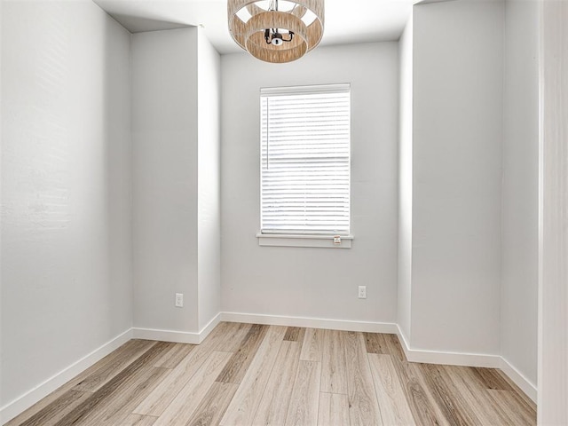 spare room featuring an inviting chandelier and light hardwood / wood-style floors