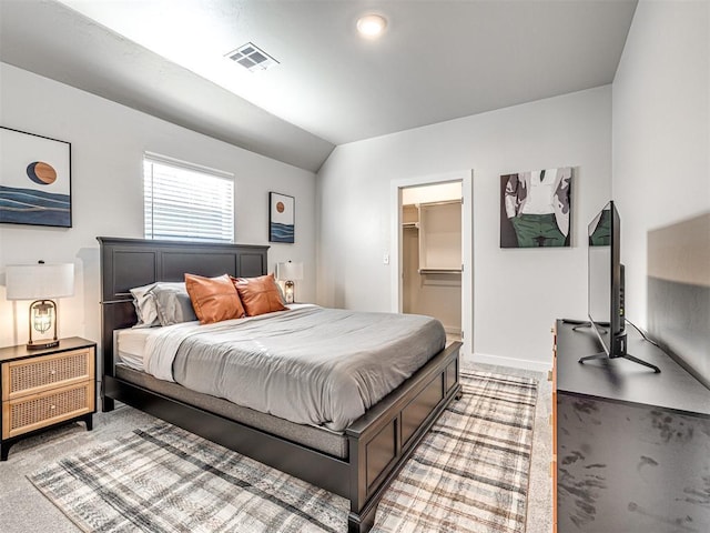 bedroom with lofted ceiling, a spacious closet, and light colored carpet