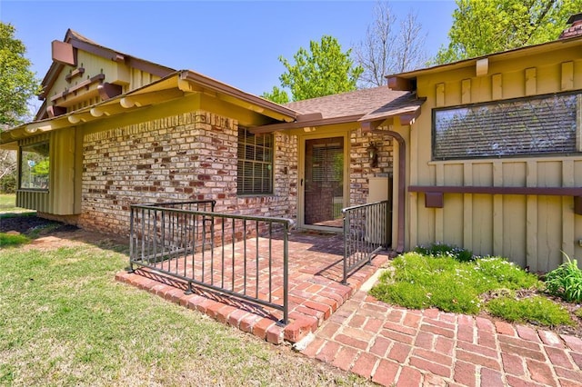 view of exterior entry with a yard and a patio