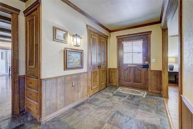 entrance foyer featuring ornamental molding and wooden walls