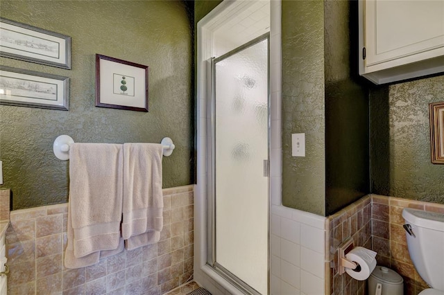 bathroom featuring an enclosed shower, tile walls, and toilet