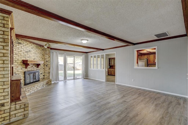 unfurnished living room featuring beam ceiling, a fireplace, crown molding, and light hardwood / wood-style flooring