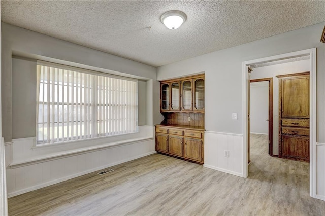 unfurnished dining area featuring light hardwood / wood-style flooring and a textured ceiling