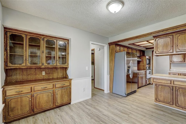 kitchen featuring stainless steel appliances, light hardwood / wood-style flooring, and a textured ceiling