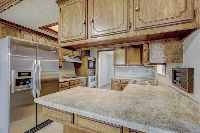 kitchen featuring sink, kitchen peninsula, a textured ceiling, and appliances with stainless steel finishes