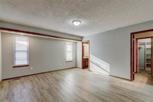 empty room with a textured ceiling and light hardwood / wood-style floors