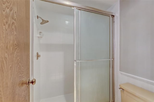 bathroom with a shower with door and toilet