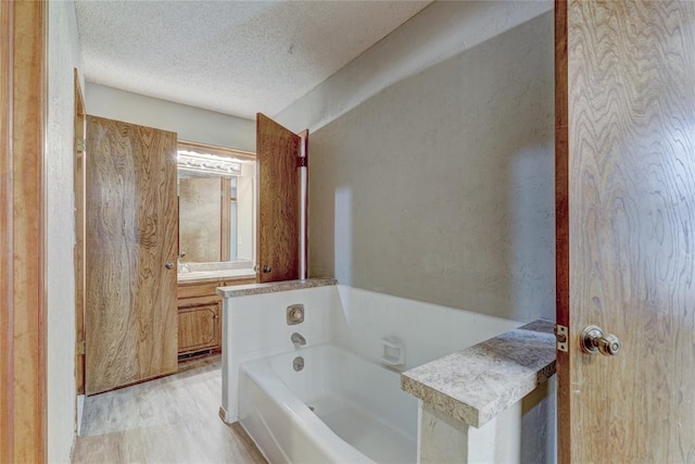 bathroom featuring vanity, a bathtub, hardwood / wood-style floors, and a textured ceiling