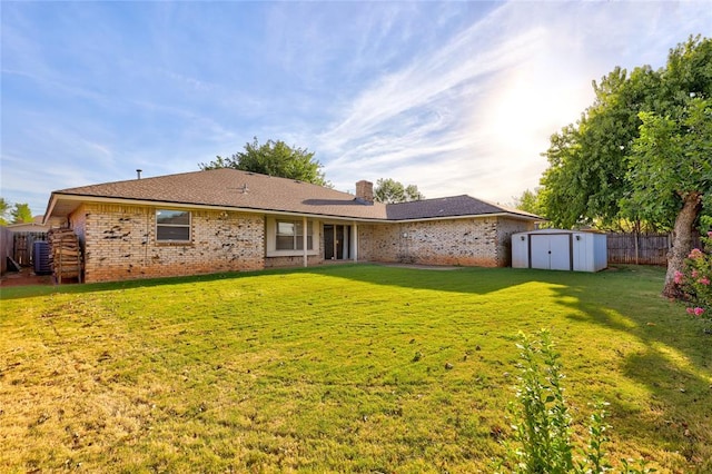 rear view of house with a lawn, central AC unit, and a storage unit