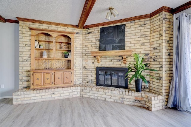 unfurnished living room with a textured ceiling, beamed ceiling, a fireplace, and light wood-style floors