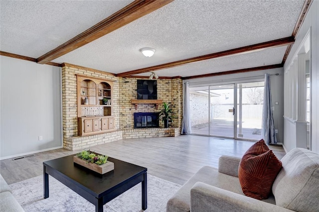 living area featuring light wood-style floors, a brick fireplace, beamed ceiling, and a textured ceiling