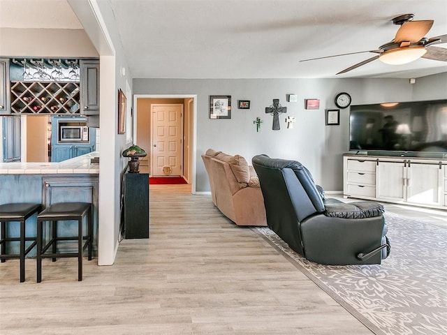 living room with ceiling fan, bar area, and light hardwood / wood-style floors