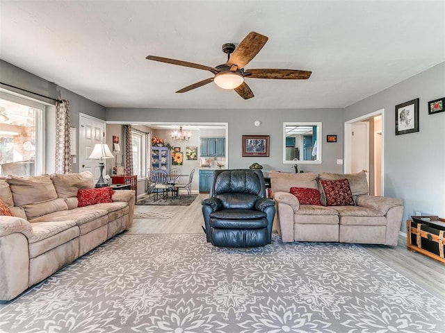 living room featuring ceiling fan with notable chandelier and light hardwood / wood-style floors