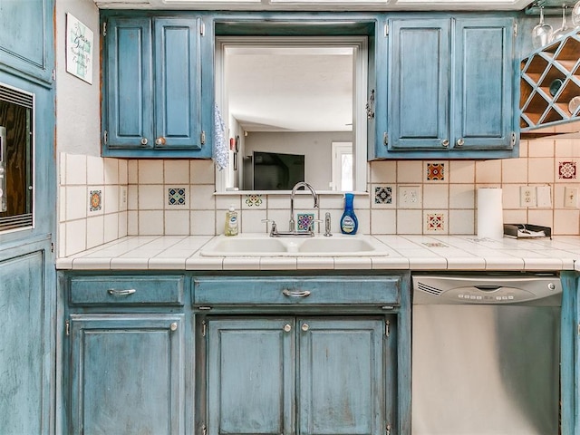 kitchen with dishwasher, sink, backsplash, tile counters, and blue cabinetry