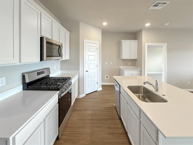 kitchen with sink, a center island with sink, dark hardwood / wood-style floors, stainless steel appliances, and white cabinets