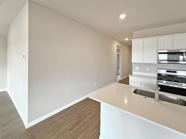 kitchen featuring stainless steel appliances, sink, hardwood / wood-style floors, and white cabinets