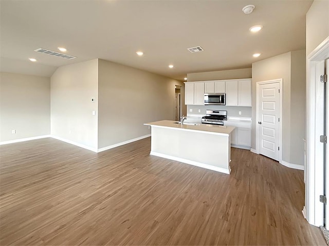 kitchen featuring sink, a kitchen island with sink, white cabinetry, stainless steel appliances, and wood-type flooring