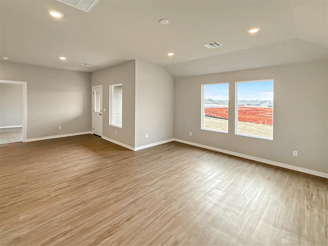 empty room with lofted ceiling and light hardwood / wood-style floors