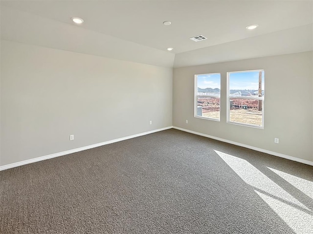 spare room with dark colored carpet and vaulted ceiling