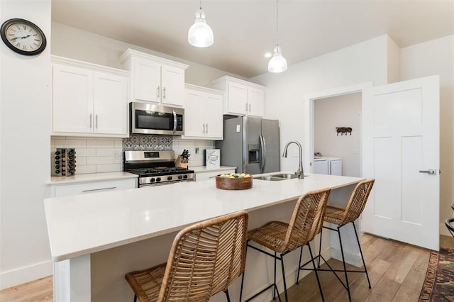 kitchen featuring separate washer and dryer, white cabinetry, a kitchen island with sink, and stainless steel appliances