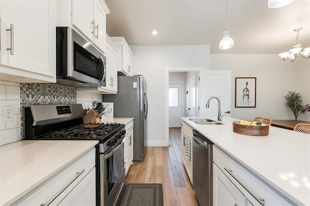 kitchen with sink, white cabinetry, tasteful backsplash, pendant lighting, and stainless steel appliances