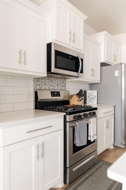 kitchen featuring stainless steel appliances, white cabinets, and backsplash