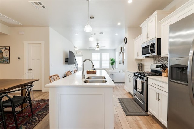 kitchen with pendant lighting, sink, a center island with sink, and appliances with stainless steel finishes