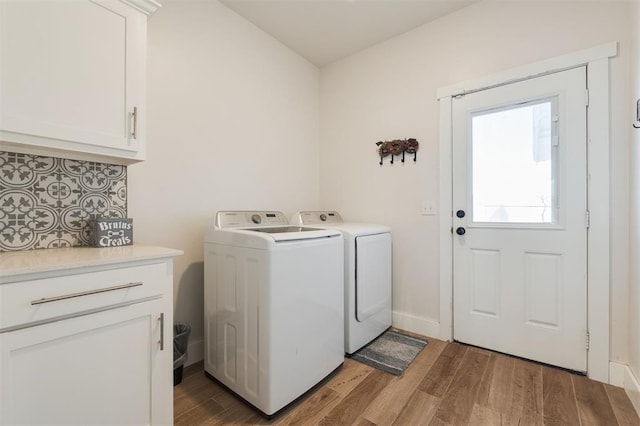 clothes washing area featuring cabinets, hardwood / wood-style flooring, and independent washer and dryer