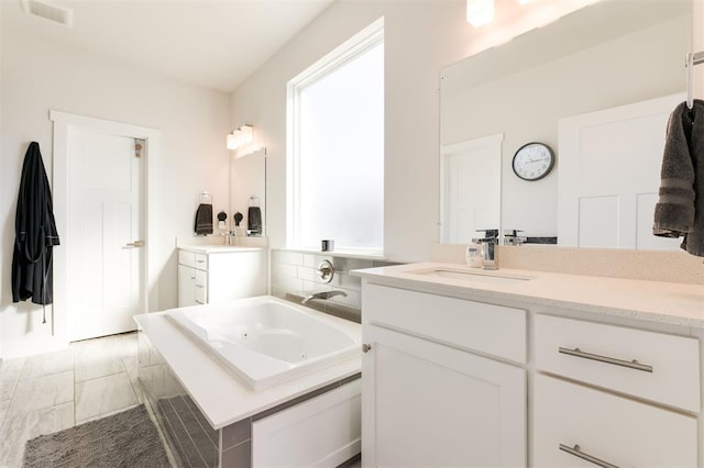 bathroom featuring vanity and tiled bath