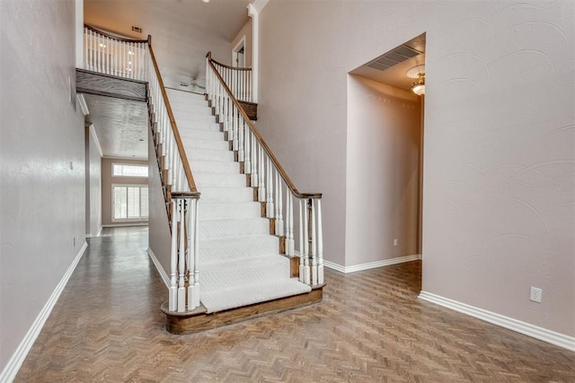 stairway featuring parquet flooring and a high ceiling