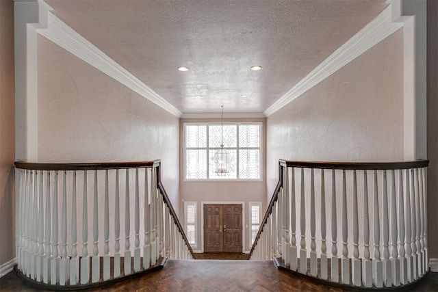 entryway featuring parquet floors, ornamental molding, an inviting chandelier, and a textured ceiling