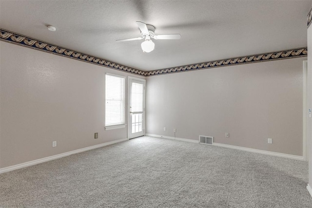 empty room with ceiling fan, carpet floors, and a textured ceiling