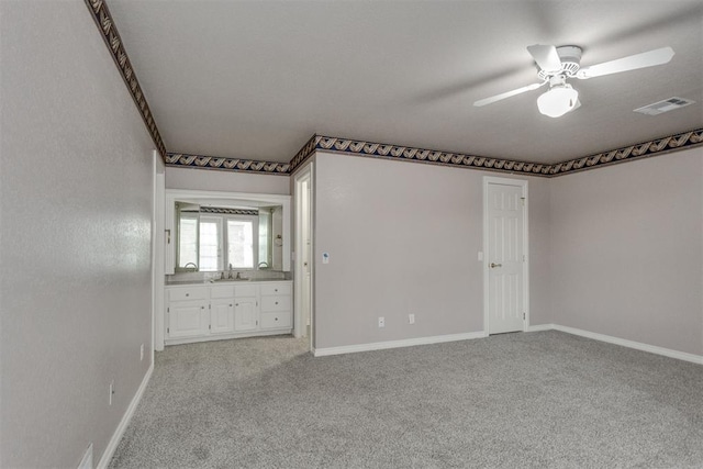 carpeted spare room featuring sink and ceiling fan