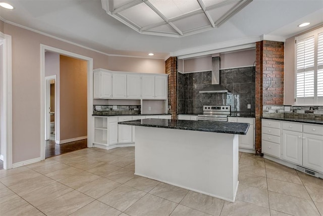 kitchen with white cabinets, a kitchen island, stainless steel electric stove, dark stone counters, and wall chimney exhaust hood