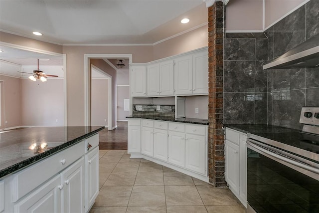 kitchen with dark stone countertops, white cabinets, decorative backsplash, stainless steel range with electric stovetop, and ceiling fan