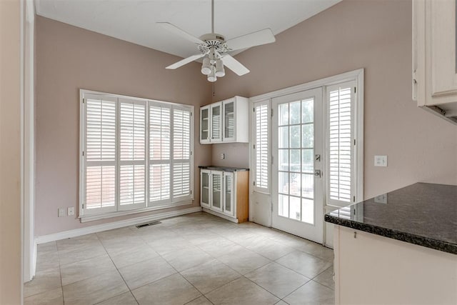 unfurnished dining area featuring light tile patterned flooring and ceiling fan