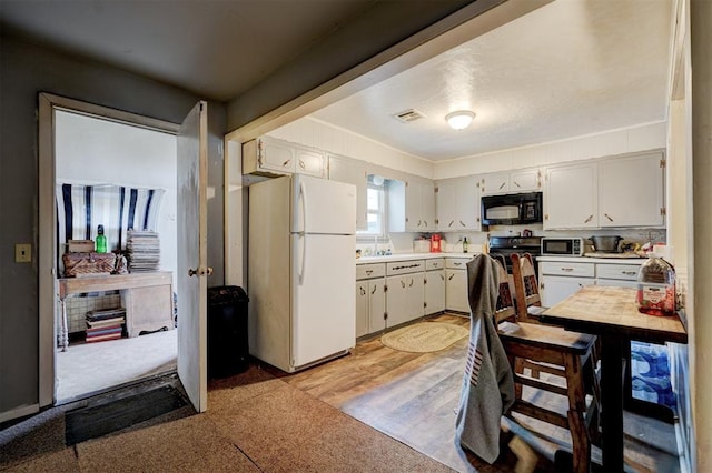 kitchen featuring white cabinetry, sink, white refrigerator, stainless steel range, and light hardwood / wood-style flooring