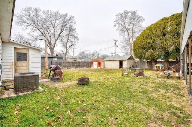 view of yard with a storage shed, a fire pit, and central air condition unit