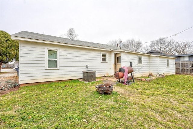 rear view of house with an outdoor fire pit and a yard