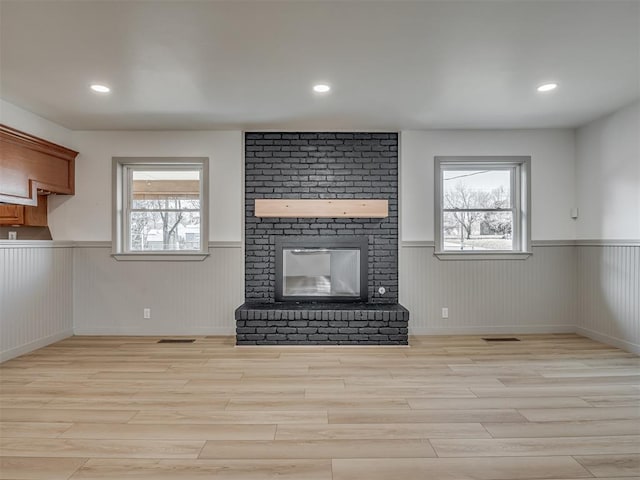 unfurnished living room featuring a fireplace and light hardwood / wood-style floors