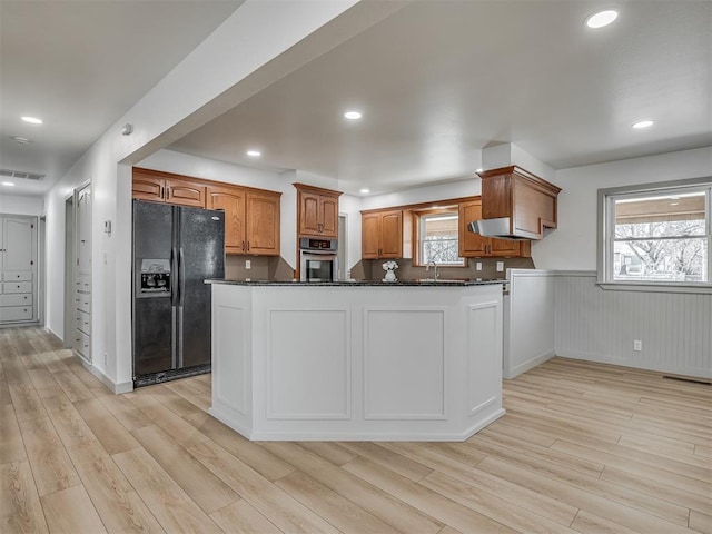 kitchen with sink, dark stone countertops, light hardwood / wood-style floors, black fridge, and oven