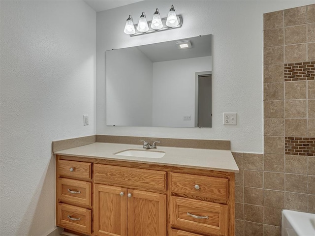 bathroom with vanity, a bathing tub, and tile walls