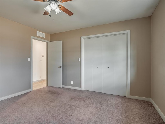 unfurnished bedroom with light colored carpet, ceiling fan, and a closet