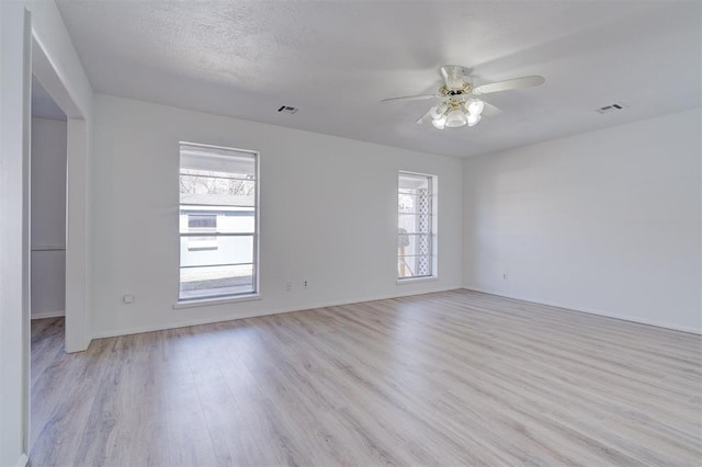 empty room with a textured ceiling, light hardwood / wood-style floors, and ceiling fan