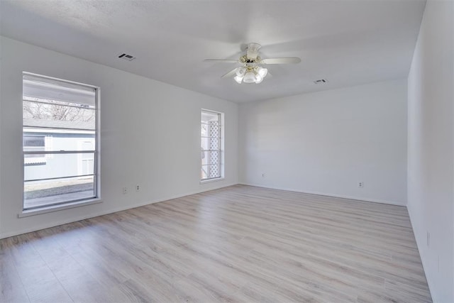 empty room with ceiling fan and light hardwood / wood-style flooring