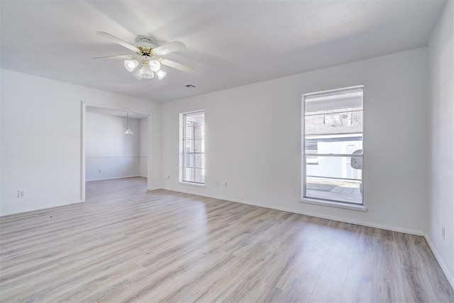 unfurnished room featuring ceiling fan, a wealth of natural light, and light wood-type flooring