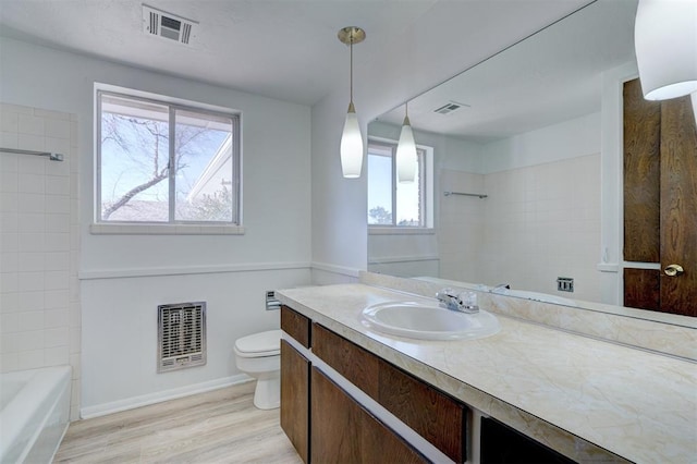 bathroom with hardwood / wood-style flooring, vanity, heating unit, and toilet